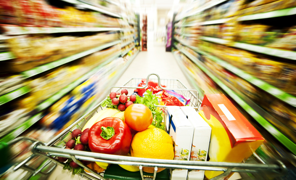 Caddie chargé de nourriture traversant une allée de supermarché