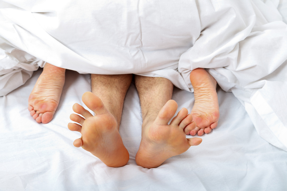 Pieds entremêlés  sous une couette