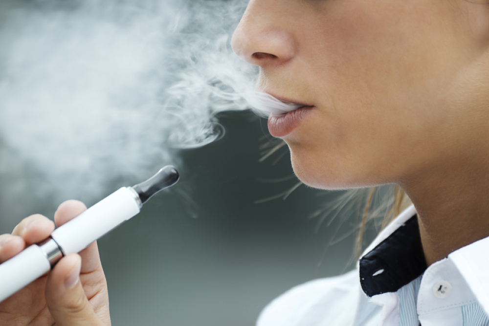 Jeune femme vapotant sur une cigarette électronique