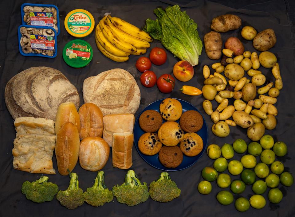 fruits légumes pains et gâteaux étalés sur une nappe noire