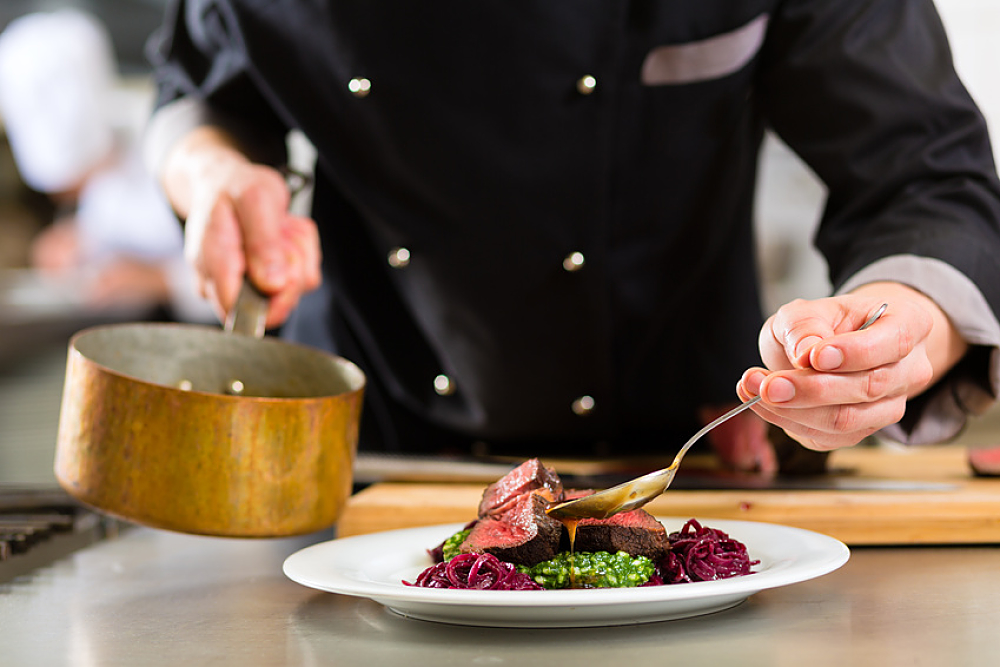 Chef cuisinier en train de dresser une assiette contenant de la viande