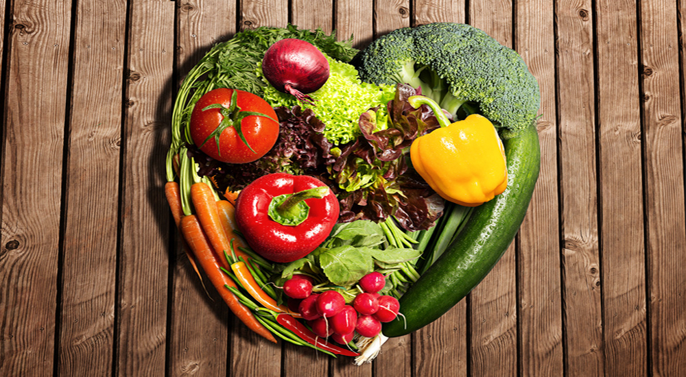 des légumes disposés en cœur sur une table en bois