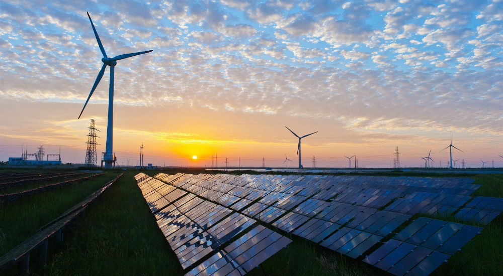 des panneaux solaires et une éolienne sous un couché de soleil