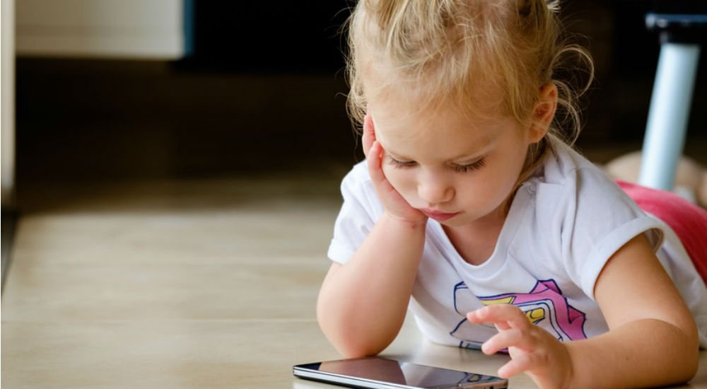 une petite fille joue sur un smartphone